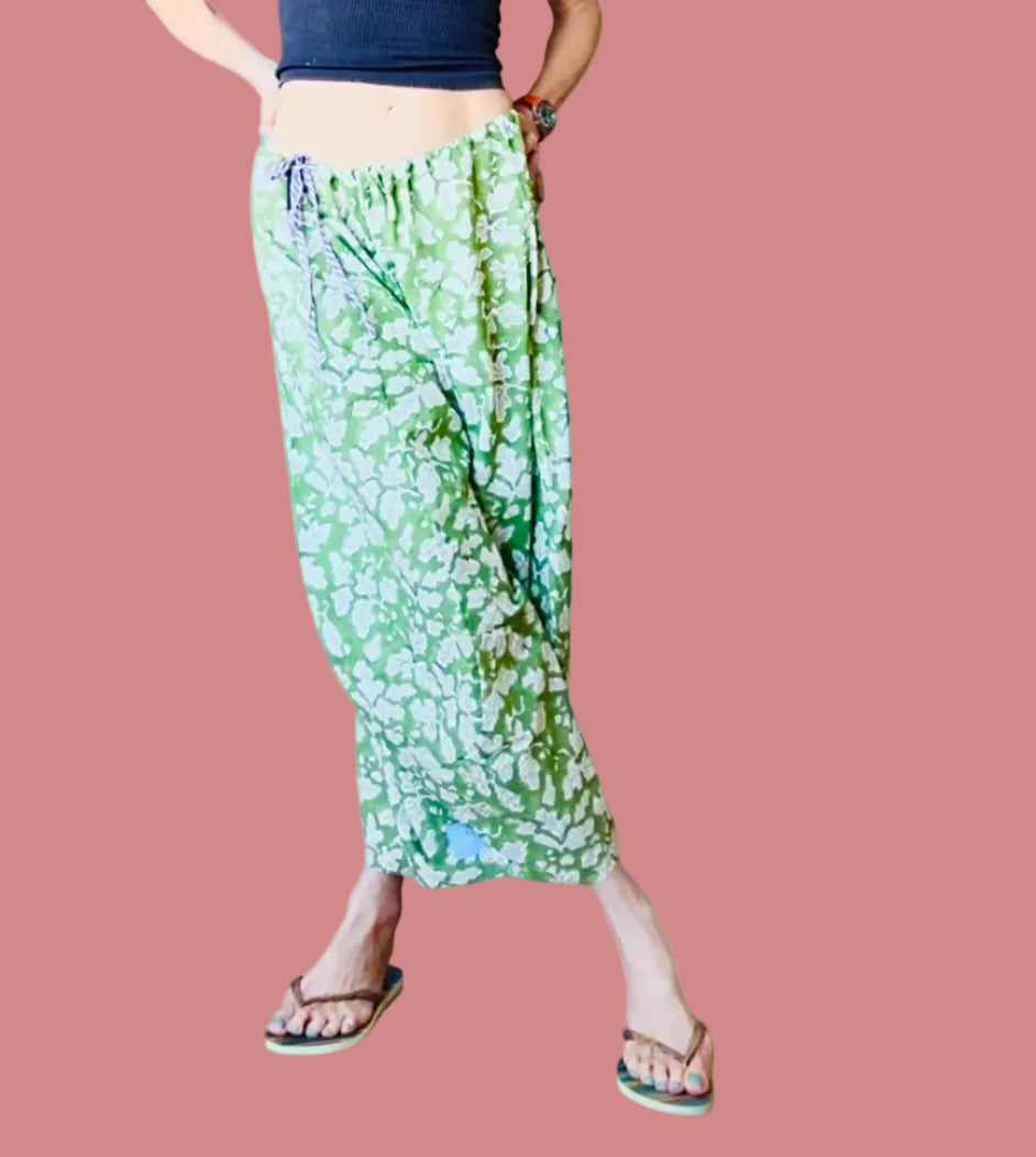 Green floral pants worn by a person on a green background