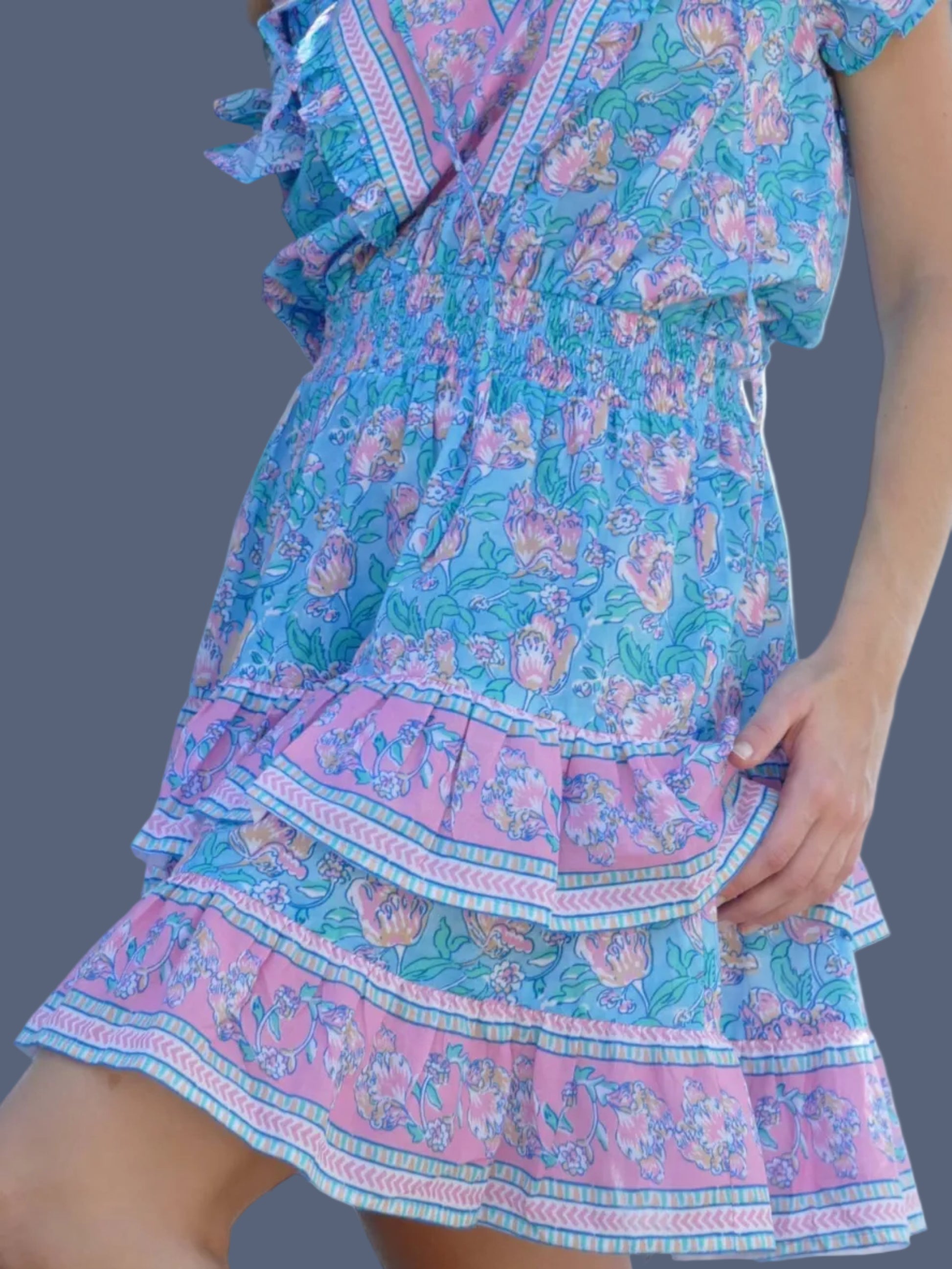 Woman in a blue and pink dress standing under a tree