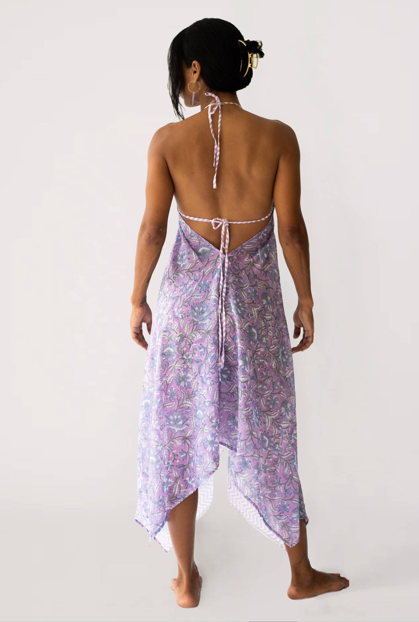 Woman wearing a purple patterned dress with a white background