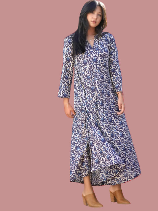 Woman wearing a blue patterned dress standing outdoors.