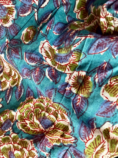 Person wearing colorful patterned pants and a black top in a minimal indoor setting.