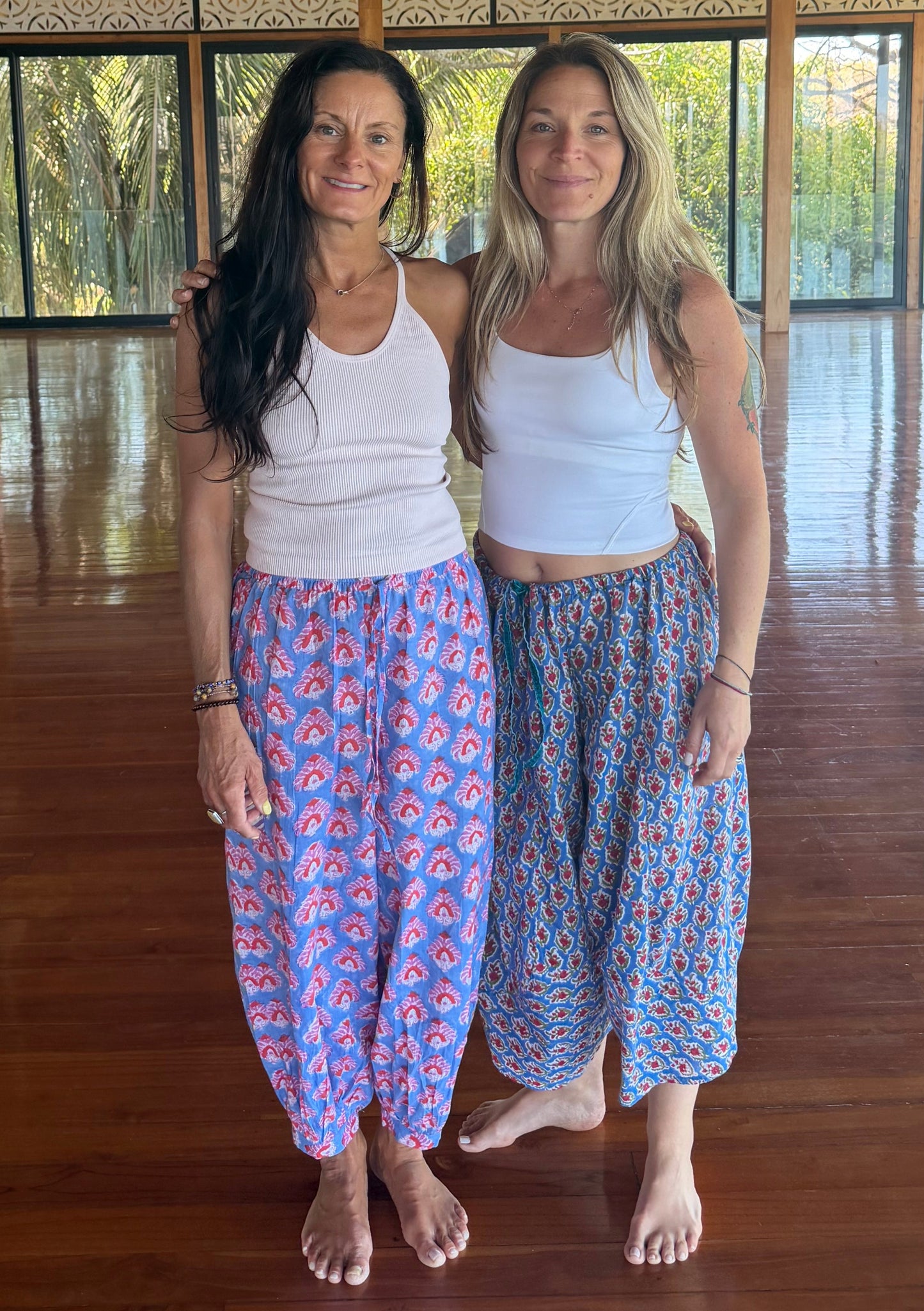 Two women standing in a room with wooden beams and large windows.